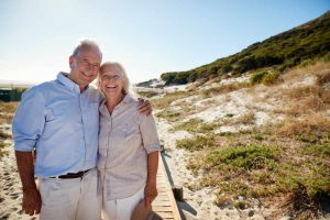 Senior white couple standing on a beach embracing