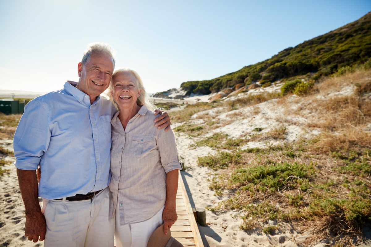 Senior white couple standing on a beach embracing
